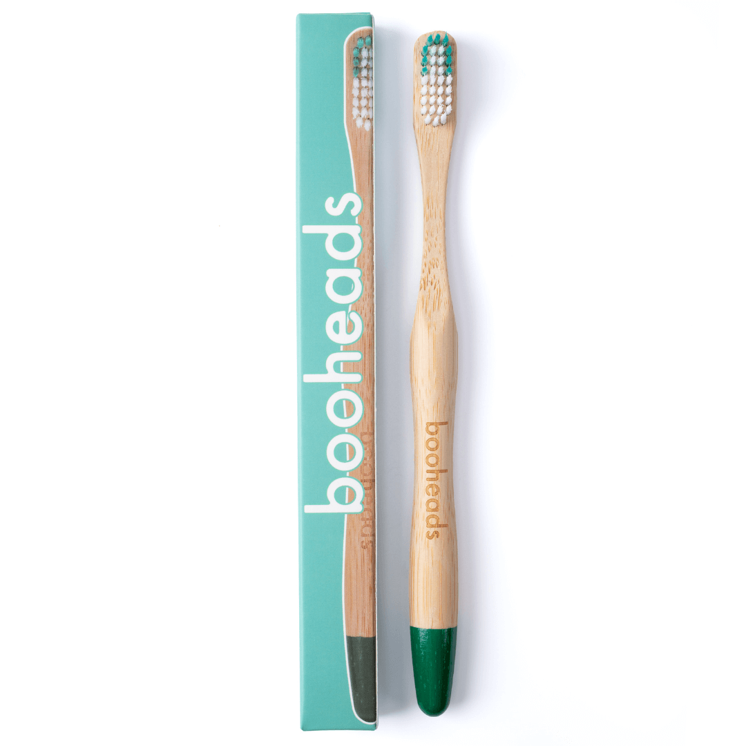 Bamboo toothbrush with green bristles and packaging on a white background