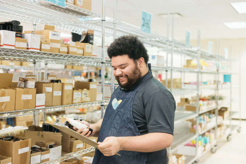 Proud news 🙏 Supporting Social Entreprise with new partnership! A worker in a warehouse reviewing items.