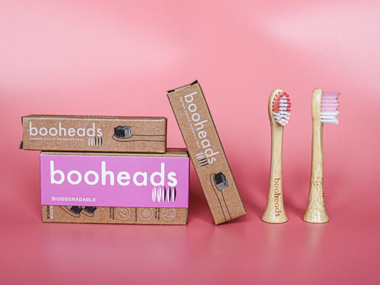 Booheads biodegradable bamboo electric toothbrush heads with eco-friendly cardboard packaging, displayed against a pink background to highlight sustainable oral care.