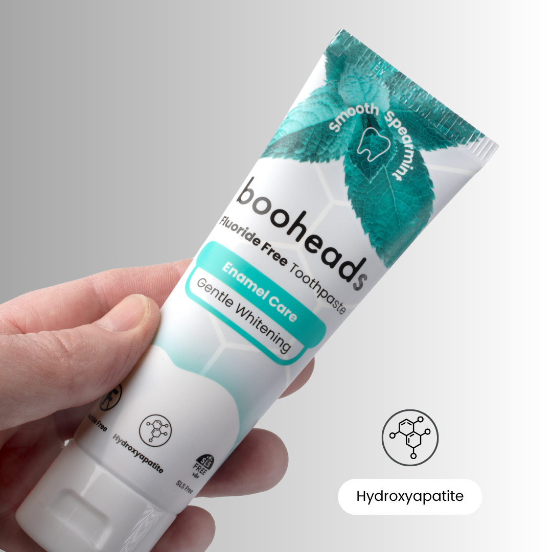 Hand holding booheads fluoride-free hydroxyapatite toothpaste, Enamel Care Gentle Whitening