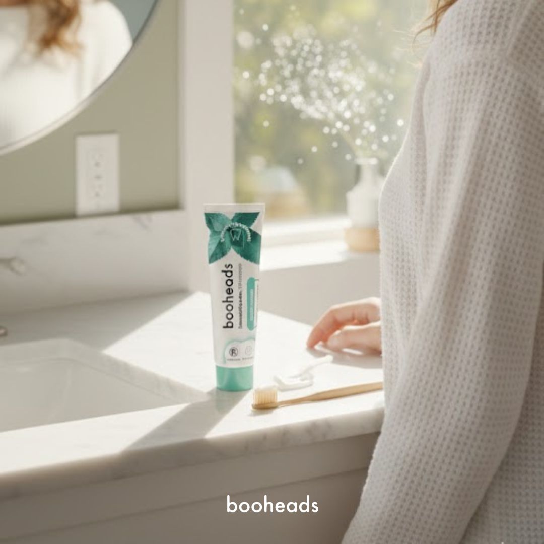 Person holding a tube of booheads toothpaste in a bathroom setting