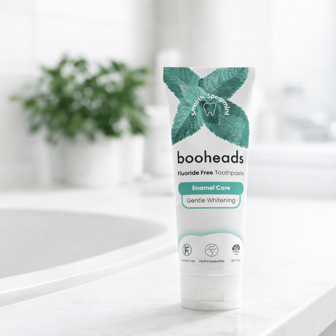 booheads fluoride-free toothpaste tube on a bathroom counter with a blurred plant in the background