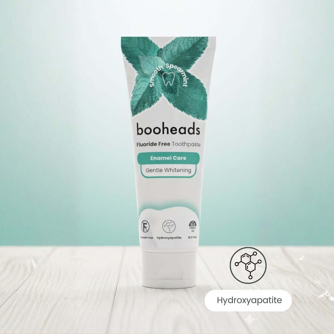 booheads fluoride-free toothpaste tube on a light wooden surface with a light blue gradient background