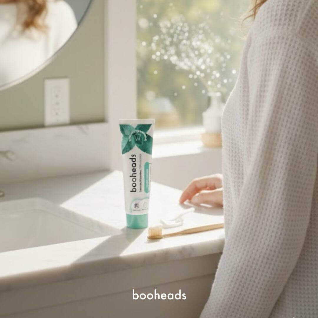 Person holding a tube of booheads toothpaste in a bathroom setting
