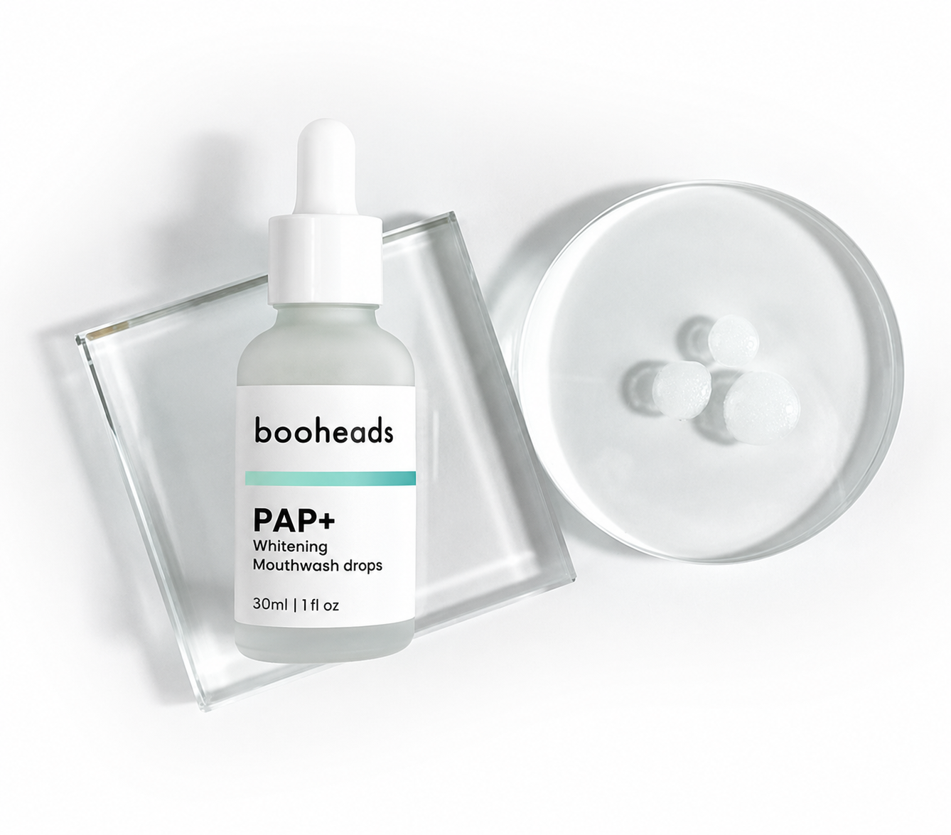 booheads PAP+ Whitening Mouthwash Drops bottle beside a dish of clear whitening serum