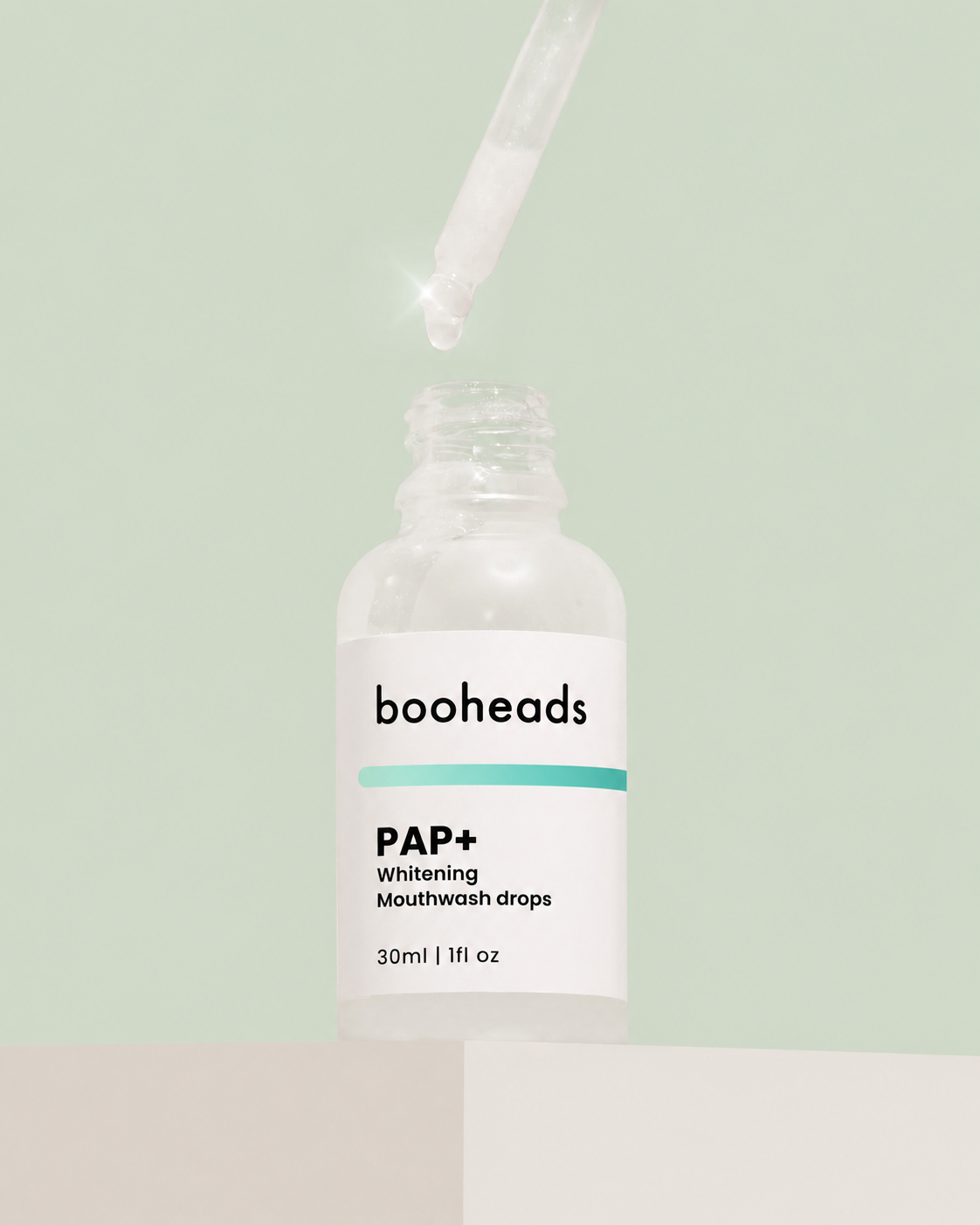 booheads PAP+ Whitening Mouthwash Drops dropper dispensing serum on a green background