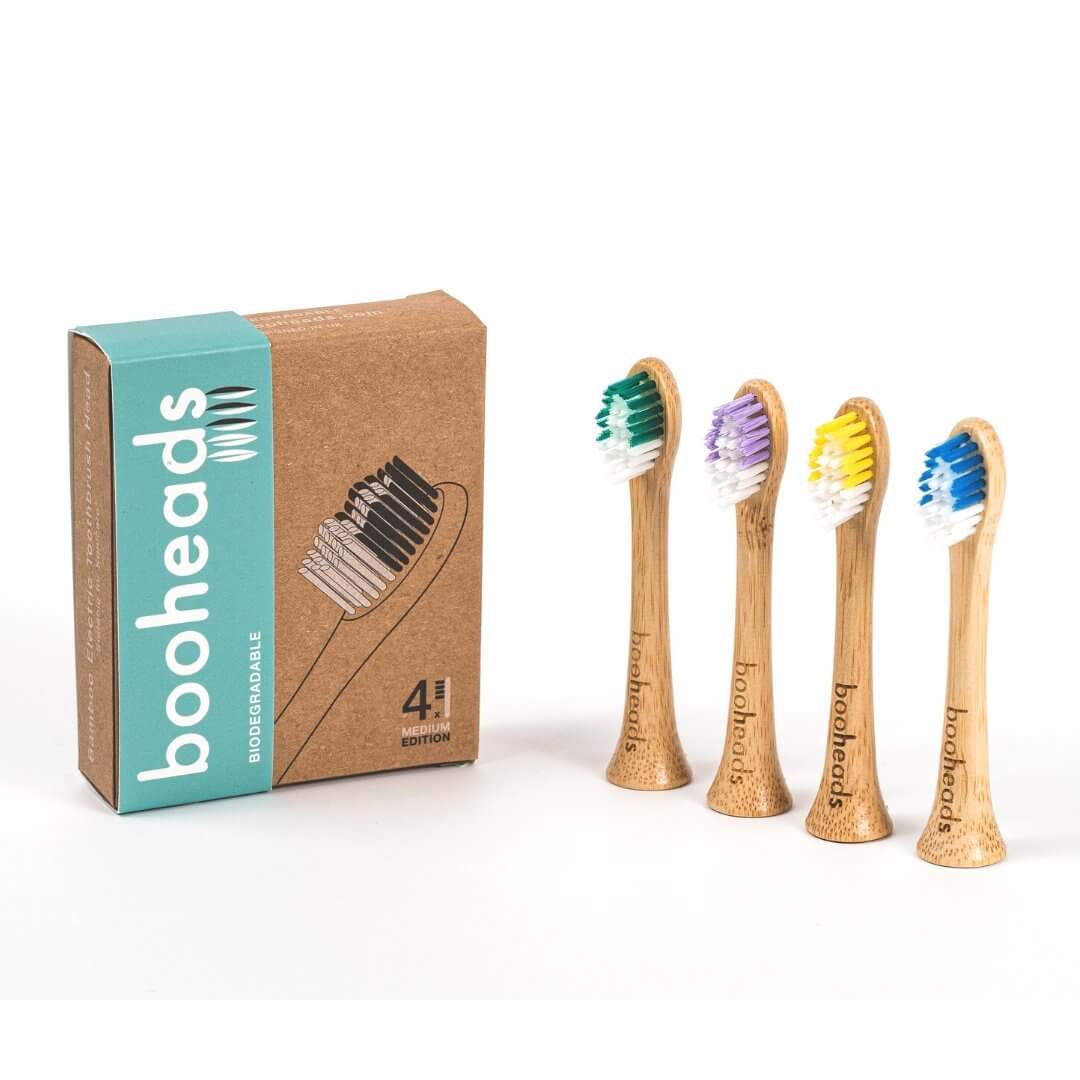 Set of bamboo toothbrushes with colorful bristles next to their packaging on a white background